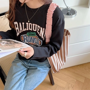 Detail of a pink pleated shoulder strap bag paired with a vintage graphic long sleeve tee