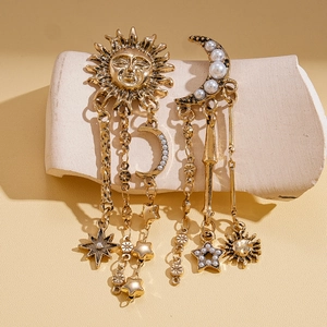 Vintage gold celestial earrings with moon star charms and faux pearls on stone pedestal