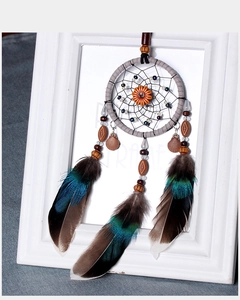 Detail of handmade dream catcher with blue-green feathers, wood beads, and shell pendants