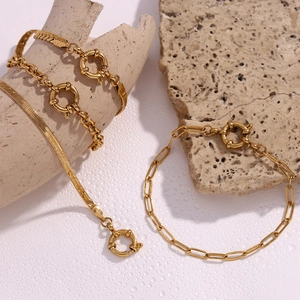 Close-up of three layered 18K gold plated chains on stone props in a minimalist style