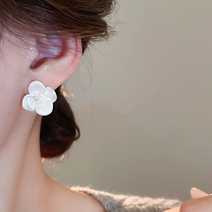 Close-up of elegant white flower stud earring with zircon center worn by a model