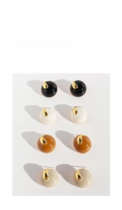 Detail showing spherical stud earrings in pearl white, black, and brown with gold metal accents