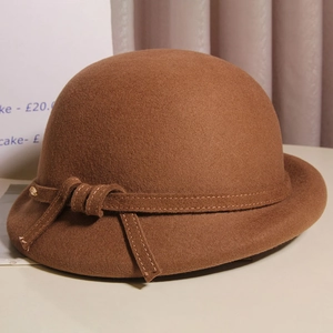 Close-up of dark brown wool felt fedora with elegant decorative ribbon and gold detail
