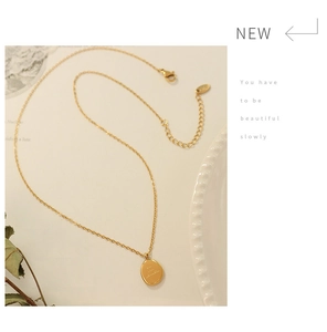 Detailed macro of a 18K gold plated oval pendant necklace with engraved lettering