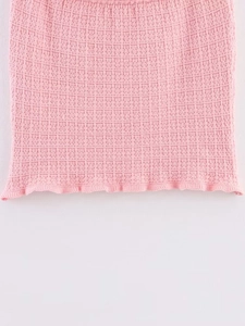 Detailed view of pink knitted dress featuring mesh texture and ruffle hemline