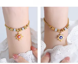 Detailed close-up of retro evil eye sun pendants on gold beaded bracelets for women