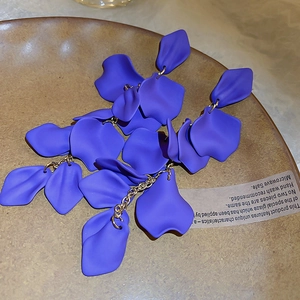 Detailed view of purple petal long tassel earrings on a textured ceramic dish