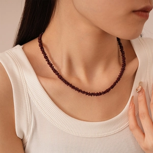 Close-up of a vintage dark red stone beaded necklace worn on a female model