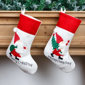 Nordic white embroidered Christmas stockings with Santa Claus hanging on fireplace