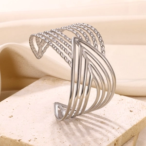 Close-up of a wide silver stainless steel cuff featuring geometric cutouts and textured bands