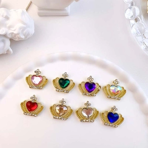 Close-up of golden crown nail charms with colorful heart-shaped rhinestones for DIY art