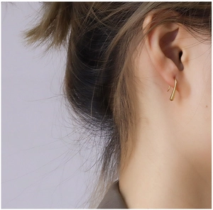 Close-up of elegant gold drop-shaped curved hook earrings on a female model