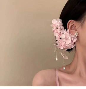 Detailed close-up of pink fabric floral hair clip with elegant pearl tassel on model