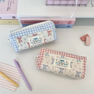 Close-up of cute gingham pattern pencil cases with embroidery on a white desk