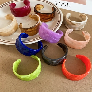 Macro detail of acrylic wavy cuff bracelets in various colors like tortoise and neon