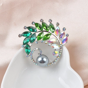 Macro detail of luxury peacock crystal brooch with grey pearl on pink silk background