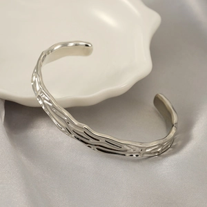 Dettaglio del bracciale rigido argento con trama irregolare lavica su ceramica bianca