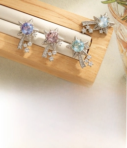 Macro detail of star-shaped brooches with colorful zircons in silver-tone titanium steel