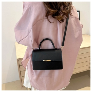 Detailed look at the black crossbody bag with gold metal buckle on model back