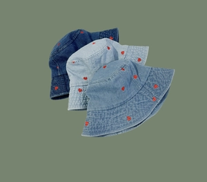 Detail of red heart embroidery on denim bucket hats in three different shades of blue
