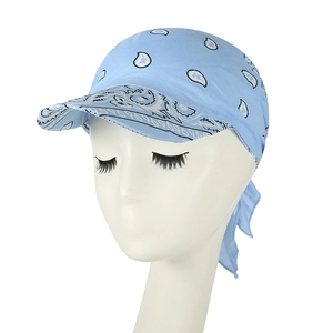 Dettaglio del berretto a bandana azzurro con motivo paisley, visiera e lacci annodati