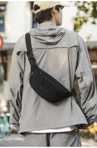 Close-up of black nylon chest bag with adjustable buckle and logo in street setting
