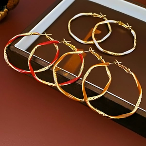 Detail of colorful enamel hoop earrings in red, orange and white on a jewelry tray