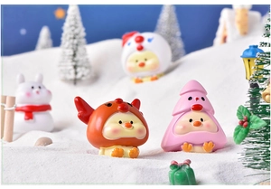 Close-up of cute cartoon chick figurines in reindeer hats on a snowy Christmas scene