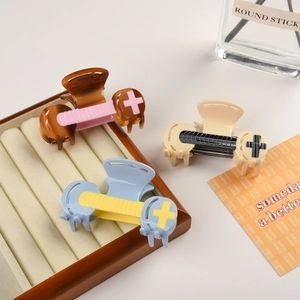 Three acetate hair claws with contrast color designs on a vintage jewelry storage box