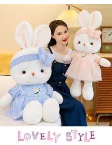 Detail of plush bunnies wearing blue and pink checkered dresses in a cozy home setting