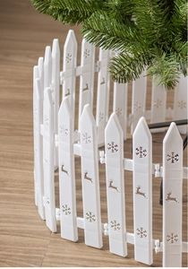 Detail of white plastic Christmas tree fence featuring hollow reindeer and snowflake patterns