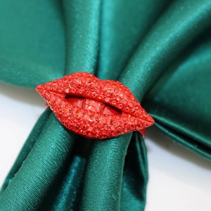 Close-up of a sparkling red lips napkin ring with crystals on a green silk napkin