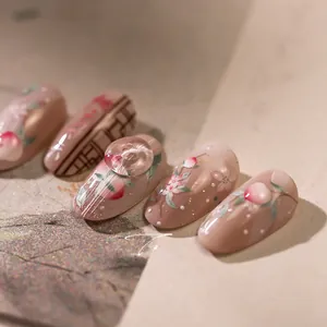 Macro view of peach-themed press-on nails with 3D crystal accents and hand-painted art