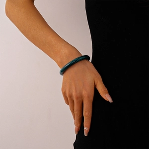 Close-up of deep green acrylic bangle with marbled pattern on a model's wrist