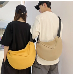 Detail of yellow and beige crescent crossbody bags worn by a couple, nylon material