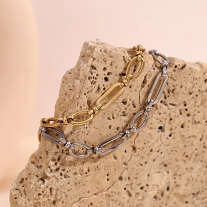 Macro shot of minimalist gold and silver paperclip link chain bracelets on stone