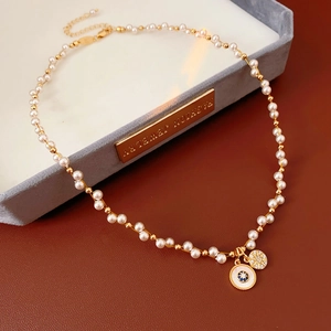 Macro view of zircon pearl necklace with blue eye pendant and sunburst charm detail