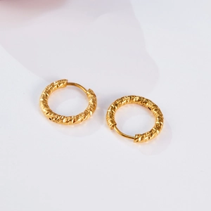 Detailed macro shot of gold hoop earrings featuring geometric diamond-cut textured patterns