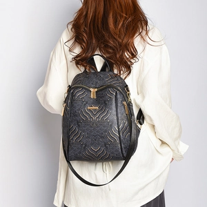 Fashionable Chinese style backpack with gold abstract patterns worn by a model in white
