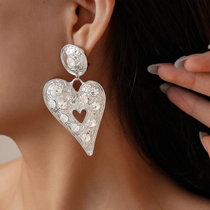 Gros plan de boucles d'oreilles cœur en argent avec cristaux brillants sur modèle