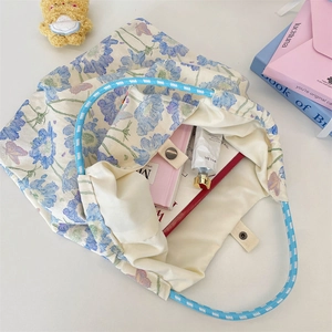 Detail of floral canvas tote bag showing the blue rope handles and secure metal snap closure