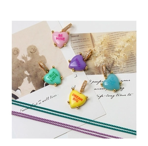 Detail of colorful enamel heart pendants with XOXO engraving and zircon-set gold clasps