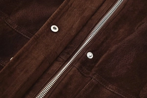Makroaufnahme von Silber-Reißverschluss und Druckknopf auf brauner Wildlederjacke