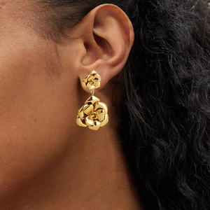 Close-up of elegant 18K gold camellia flower drop earrings on model with retro vintage style