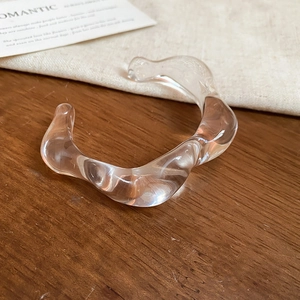 Macro detail of clear acrylic wave bracelet with minimalist irregular liquid texture