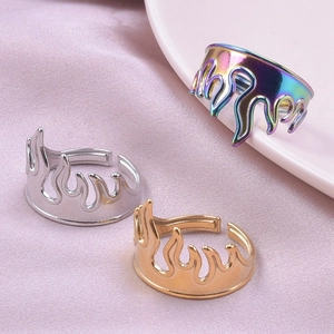 Detailed shot of gold, silver, and rainbow flame-patterned adjustable open rings on silk
