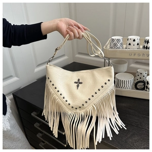 Detail of studded crescent crossbody bag featuring vintage fringe and metal hardware