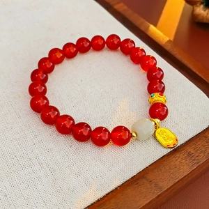 Détail du bracelet en perles d'agate rouge avec pendentif Fu doré et perle de jade blanc