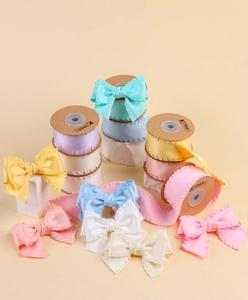 Détail de rubans satinés à bords volantés aux couleurs macaron sur bobines artisanales
