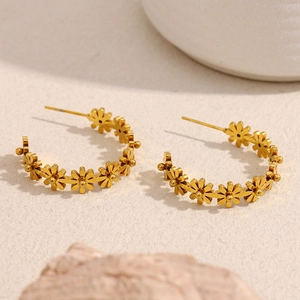 Détail macro de boucles d'oreilles créoles dorées en forme de marguerite avec texture florale
